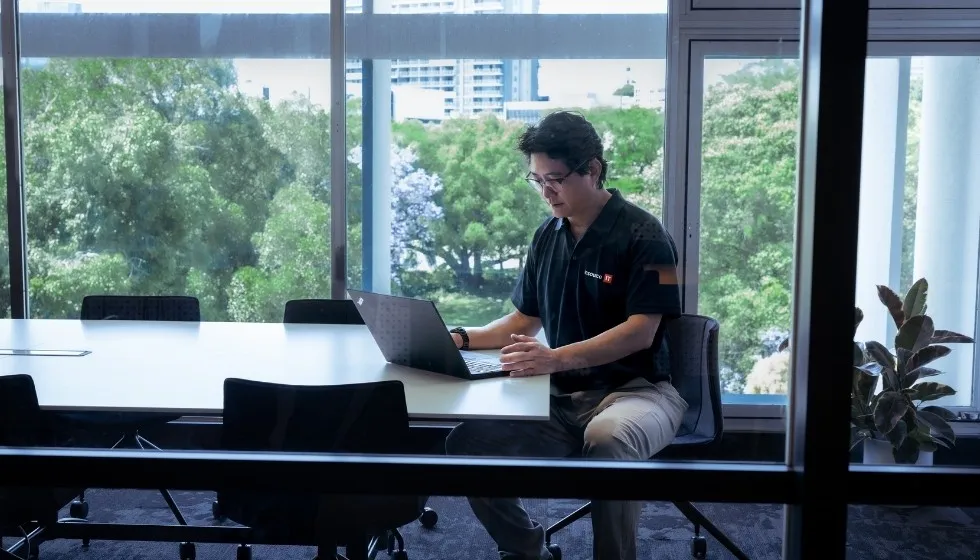 Team member working at a laptop by a window